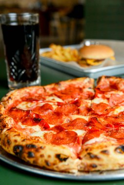 Sıcak Chilli Pepperoni Pizza, yemek için hazır. Bir restoranda servis edilen kırmızı biberli, dilimlenmiş salamlı pizza..