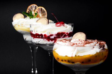 Tiramisu farklı şekillerde, tiramisu servis etmenin çeşitli şekillerinde. Farklı dolgulu geleneksel tatlı. Çikolata, hindistan cevizi, tutku meyvesi, kiraz ve limon. Siyah arkaplanda.