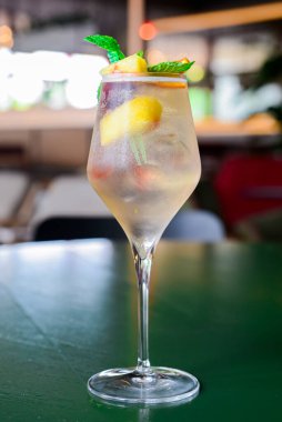 Mango ve tutkulu meyve kokteyli naneli. Yeşil arka planda uzun bir bardakta lezzetli bir meyve suyu. Alkolik içecek..