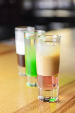 Üç çeşit alkollü içki, arka planda bulanık duran ahşap bir masayı gizler. Restoran ya da bar, parti konsepti.