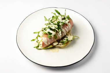 Ispanak ve roka ile ızgara tavuk filetosu. Lezzetli sağlıklı yiyecekler. Üstüne krema sosu dökülmüş. Beyaz arka planda beyaz bir plaka ile servis edilmiş..