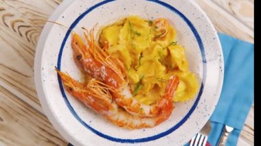 Ravioli 'yi karides ya da langoustine ile kapayın, beyaz bir tabakta ahşap masa arkasında servis edin. İtalyan mutfağı konsepti. Geleneksel tarifle yapılan ravioli yemek..
