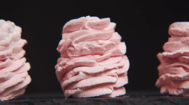 Siyaha servis edilen üç pembe zephyr kurabiyesinde panorama manzarasını kapat. Şekerleme ya da zephyr - tatlı çilek tadı. Siyah üzerine tatlı yavaş çekim görüntüsü.