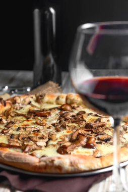 Kırsal ahşap arka planda mantarlı pizza. Lezzetli vejetaryen pizza. Geleneksel tarif, İtalyan mutfağı konsepti. Kırmızı şarapla servis edilir..