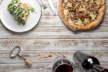 Kırsal ahşap arka planda mantarlı pizza. Lezzetli vejetaryen pizza. Ispanak ve roka ile ızgara tavuk filetosu. Kırmızı şarap. Boşluk afişini kopyala.