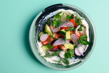 Sebzeli salata - domates, salatalık, merhem, taze maydanoz ve dereotu. Nane yeşili arka planda bir kasede servis edilmiş. Sağlıklı beslenme,