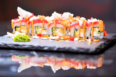 Somon, ton balığı, avokado, krem peynir ve tutkulu meyve sosuyla Philadelphia usulü suşi. Suşi menüsü. Japon yemeği. Yakın çekim, seçici odaklanma, bulanık bir arka plan. Geleneksel tarif.