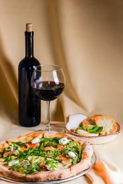 Mozarellalı pizza, somon dilimleri, taze roka. Fırında peynirli camembert ve kırmızı şarapla servis edilir. İtalyan mutfağı, geleneksel pizza tarifi..