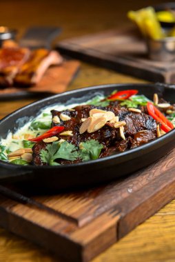 Kırsal ahşap arka planda, tencerede sosla servis edilen sebzeli et. Rustik tarzı akşam yemeği, Ukrayna mutfağı konsepti.