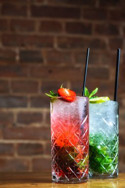 Kokteyl koleksiyonu: Çilek ve bardakta klasik mojito. Yaz menüsü, içeride iki içki. Uzayı dikey olarak kopyala.