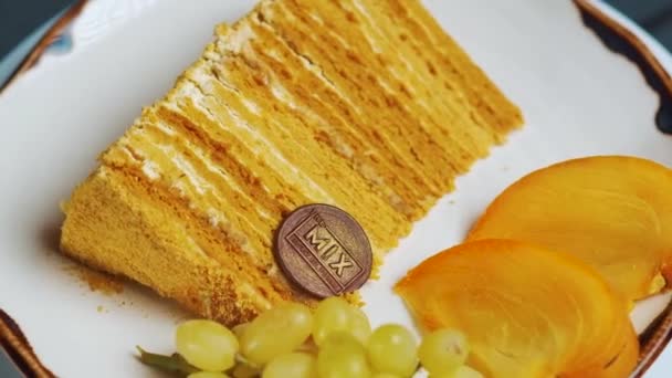 新烤的蜂蜜蛋糕放在白盘上 蜂蜜蛋糕 切片在一个白色的盘子 在一个孤立的白色背景 吃新鲜蜂蜜蛋糕 — 图库视频影像