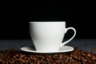 Siyah arka planda kahve çekirdekleri olan bir fincan sıcak kahve. Kahve zamanı, web sitesi tasarım afişini kopyala. Siyah arkaplanda beyaz bardak.