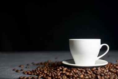 Siyah arka planda kahve çekirdekleri olan bir fincan sıcak kahve. Kahve zamanı, web sitesi tasarım afişini kopyala. Siyah arkaplanda beyaz bardak.