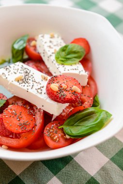 Çilekli Caprese salatası, mozzarelller, fesleğen ve balzamik sos yeşil ekose arka planda beyaz bir kasede servis edilir. İtalyan mutfağı konsepti, yaz menüsü, geleneksel çilekli tarifi..