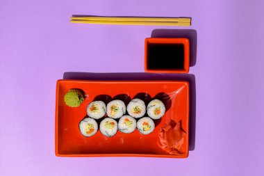 Japon suşi ruloları kırmızı bir tabakta turşulu zencefil ve wasabi sosuyla servis ediliyor. Japon mutfağı konsepti. Geleneksel suşi maki rulo tarifi.