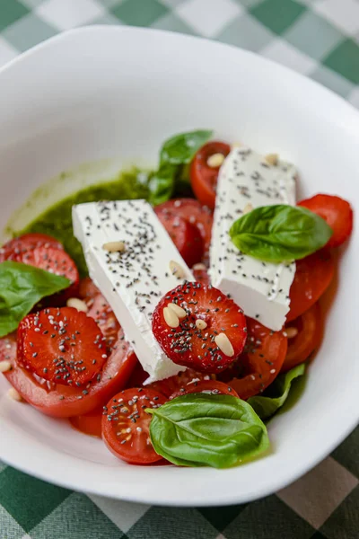 Çilekli Caprese salatası, mozzarelller, fesleğen ve balzamik sos yeşil ekose arka planda beyaz bir kasede servis edilir. İtalyan mutfağı konsepti, yaz menüsü, geleneksel çilekli tarifi..