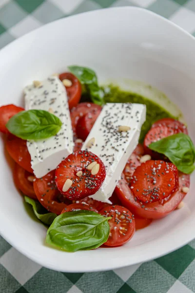 Çilekli Caprese salatası, mozzarelller, fesleğen ve balzamik sos yeşil ekose arka planda beyaz bir kasede servis edilir. İtalyan mutfağı konsepti, yaz menüsü, geleneksel çilekli tarifi..