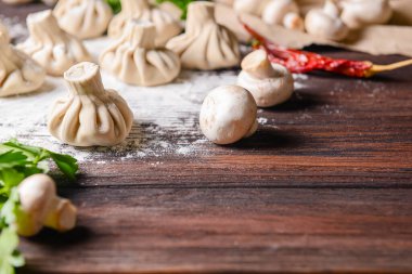 Gürcü köftesi ya da Khinkali. Ahşap arka planda ev yapımı Gürcistan Khinkalisi. Yan görüş, seçici odaklanma. Taze yeşillik, baharat ve çiğ mantarla. Boşluk afişini kopyala.