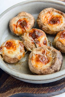 Geleneksel Gürcistan yemeği doldurulmuş mantarlar bir kasede servis edilir ve kırsal ahşap masa üzerinde bir sürü taze yeşillik vardır. Peynirli mantarlar..