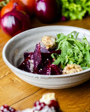 Rendelenmiş pancar salatası ve kırsal ahşap arka planda bir kasede bir sürü taze yeşillik bulunan otlar. Gürcistan mutfağı konsepti, Gürcistan geleneksel menüsü.