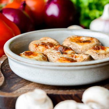 Geleneksel Gürcistan yemeği doldurulmuş mantarlar bir kasede servis edilir ve kırsal ahşap masa üzerinde bir sürü taze yeşillik vardır. Peynirli mantarlar..