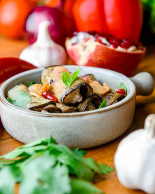 Peynirle doldurulmuş sağlıklı patlıcan ruloları geleneksel bir kasede servis ediliyor ve masada bir sürü taze sebze, meyve ve sebze var. Gerogian mutfak konsepti, menü.