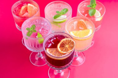 Gürcistan mutfağı kavramı. Bardaktaki farklı meyve sularından yapılmış buzlu soğuk içecekler. Parlak pembe arkaplanda servis edilir.