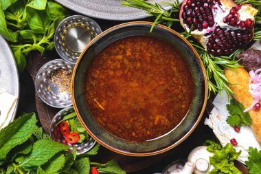 Baharatlar, taze yeşillikler ve sebzelerle çevrili köy sofrasında etli Harço çorbası. Geleneksel Gürcü mutfağı konsepti. Manzara, yemek fikri..