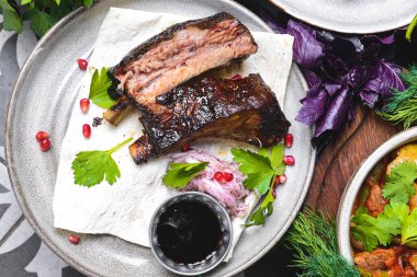 Lokantada servis edilen soğan ve sosla birlikte seramik tabakta servis edilen kemiğin üzerinde et bulunan sağlıklı ve sulu bir domuz pirzolası. Gürcistan mutfağı konsepti, üst manzara.