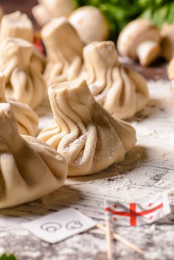 Gürcü köftesi ya da Khinkali. Ahşap arka planda ev yapımı Gürcistan Khinkalisi. Yan görüş, seçici odaklanma. Taze yeşillik, baharat ve çiğ mantarla.