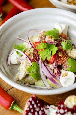 Domatesli salata, peynir ve tatlı ve ekşi soslu kişniş. Gürcistan mutfağı. Sağlıklı yiyecekler. Kırsal ahşap masada diğer tabaklarla birlikte bir kasede servis edilmiş..