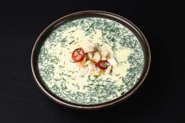 Yazın soğuk yoğurt çorbası okroshka ile siyah arka planda servis edilen mavi bir kase içinde tavuk. Kroshka 'nın geleneksel tarifi.