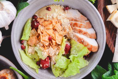 Tavuk göğsü, peynir ve domatesli taze salata. Tahta bir masada bir kasede servis edilmiş ve bir sürü taze yeşillik var. Gürcistan mutfağı kavramı.