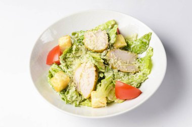 Sezar Salatası beyaz arka planda beyaz bir kasede servis edildi. Sezar salatasının geleneksel tarifi, seçici odaklanma, bulanık arkaplan.