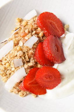 Bir kase taze çilekli sıcak yulaf ezmesi. Sağlıklı bir kahvaltı kadar mükemmel. Beyaz kasede ekşi kremayla servis ediliyor. Kahvaltı konsepti.