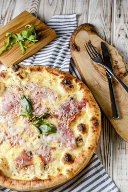 Kırsal ahşap masada pizza dilimlenmiş bir bardak kırmızı şarap. İtalyan mutfağı kavramı, jambonlu ve peynirli pizza, beyaz arka plan..