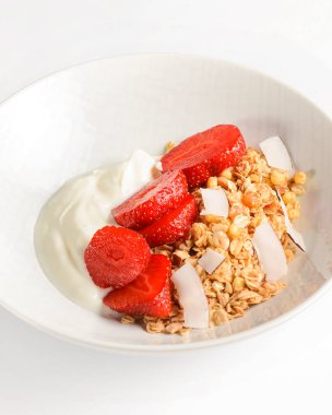 Bir kase taze çilekli sıcak yulaf ezmesi. Sağlıklı bir kahvaltı kadar mükemmel. Beyaz kasede ekşi kremayla servis ediliyor. Kahvaltı konsepti.