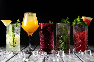 Renkli yaz içecekleri, alkollü içecekler ve koyu arkaplanda zarif bardaklarda kokteyller. Mohito kokteylinin farklı türleri..