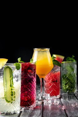 Renkli yaz içecekleri, alkollü içecekler ve koyu arkaplanda zarif bardaklarda kokteyller. Mohito kokteylinin farklı türleri..