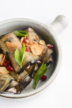 Peynirle doldurulmuş sağlıklı patlıcan ruloları beyaz arka planda taze yeşilliklerle servis edilen geleneksel bir kasede servis edilir. Gerogian mutfak konsepti, menü.