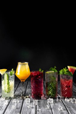 Renkli yaz içecekleri, alkollü içecekler ve koyu arkaplanda zarif bardaklarda kokteyller. Mohito kokteylinin farklı türleri..