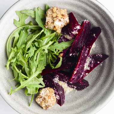 Rendelenmiş pancar salatası ve beyaz arka planda bir kasede taze yeşillik içeren otlar. Gürcistan mutfağı konsepti, Gürcistan geleneksel menüsü.