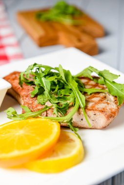 Taze yeşil roka, portakal dilimleri ve domates sosuyla servis edilmiş ızgara biftek. Beyaz bir tabakta. İtalyan mutfağı kavramı.