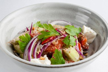 Domatesli salata, peynir ve tatlı ve ekşi soslu kişniş. Gürcistan mutfağı. Sağlıklı yiyecekler. Kırsal ahşap masada diğer tabaklarla birlikte bir kasede servis edilmiş..