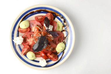 Beyaz arka planda beyaz tabakta servis edilen fesleğenli geleneksel Caprese Salatası. Beyazda izole edilmiş. İtalyan mutfağı konservesi. Geleneksel tarif.