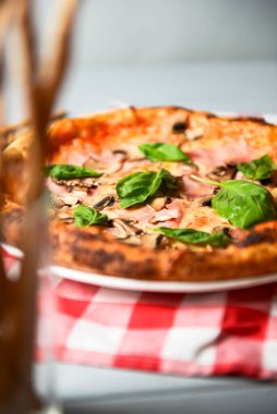 Mantarlı iştah açıcı pizza ve hafif ahşap arka planda taze fesleğen. İtalyan mutfağı kavramı, taze pişmiş pizza.