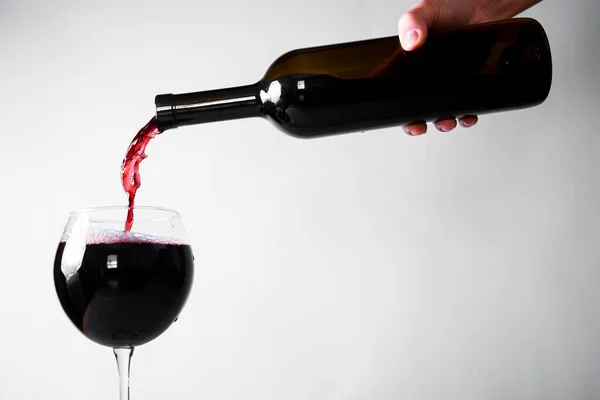 Red wine pouring down from a wine bottle into a wine glass over white background. Banner with copy space. Wine concept.