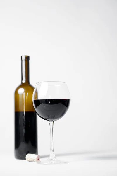 Red wine bottle without a label and glass filled iwth red wine. Over white background. Copy space banner. Wine concept.
