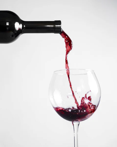 Red wine pouring down from a wine bottle into a wine glass over white background. Banner with copy space. Wine concept.