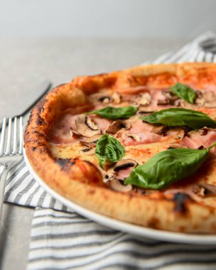 Mantarlı iştah açıcı pizza ve hafif ahşap arka planda taze fesleğen. İtalyan mutfağı kavramı, taze pişmiş pizza.